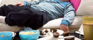 Niño recostado sobre un sofá con comida y bebida chatarra