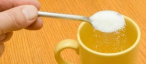 Cucharita de sustituto de azúcar al borde de una taza