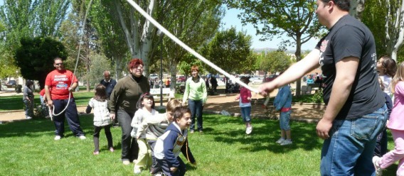 Niñas y niños juegan a saltar la cuerda, que impulsan adultos