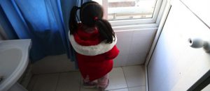 Niña mirando por la ventana hacia afuera