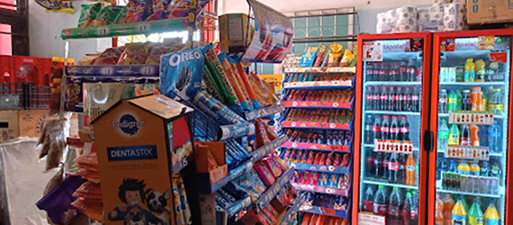Interior de una tienda con refrigeradores de refrescos al fondo